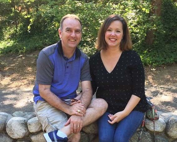 A man and a woman are sitting next to each other on a rock wall.