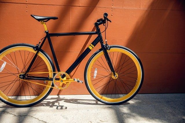 A black and yellow bicycle is parked in front of a brown wall.