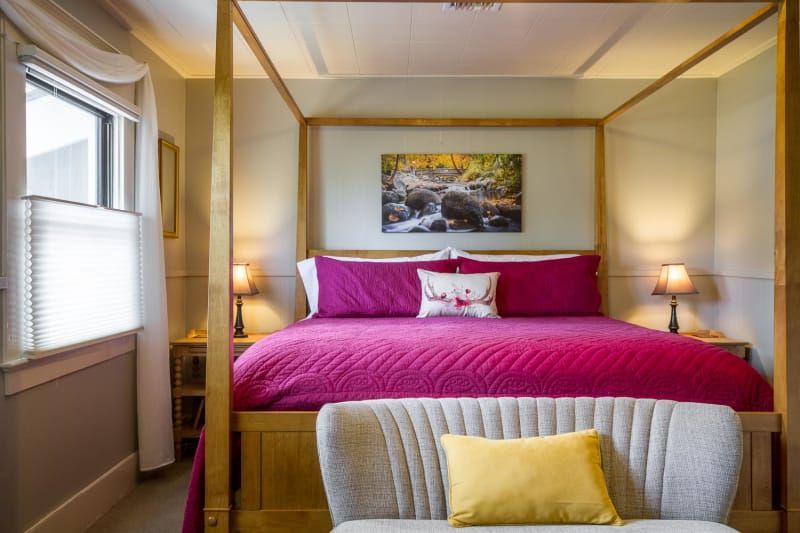 A bedroom with a four poster bed and a couch.