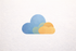 Een gestileerd icoon van drie overlappende, gestructureerde wolken in tinten blauw, lichtgroen en oranje op een witte achtergrond.
