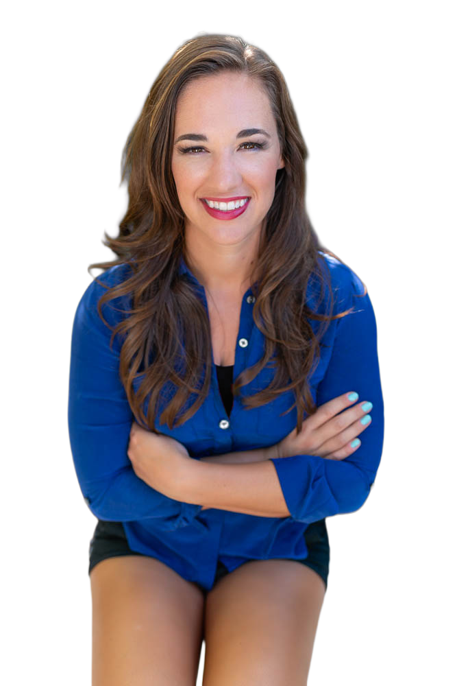 Smiling woman in a blue shirt and black shorts sitting with arms crossed against a white background