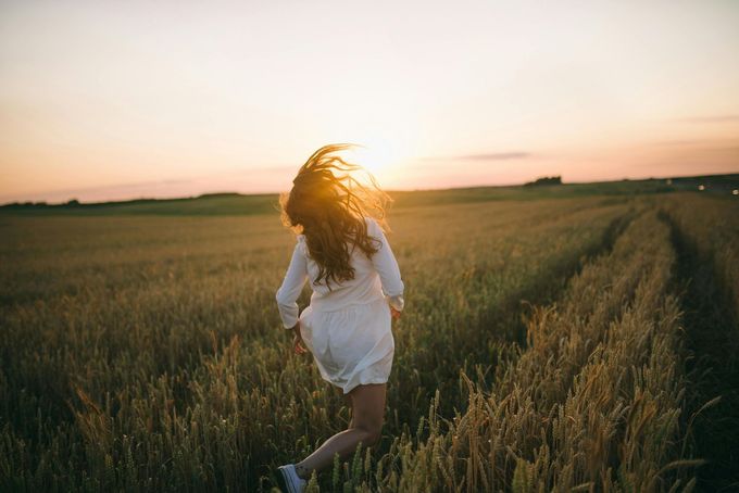 Woman running in field at sunset