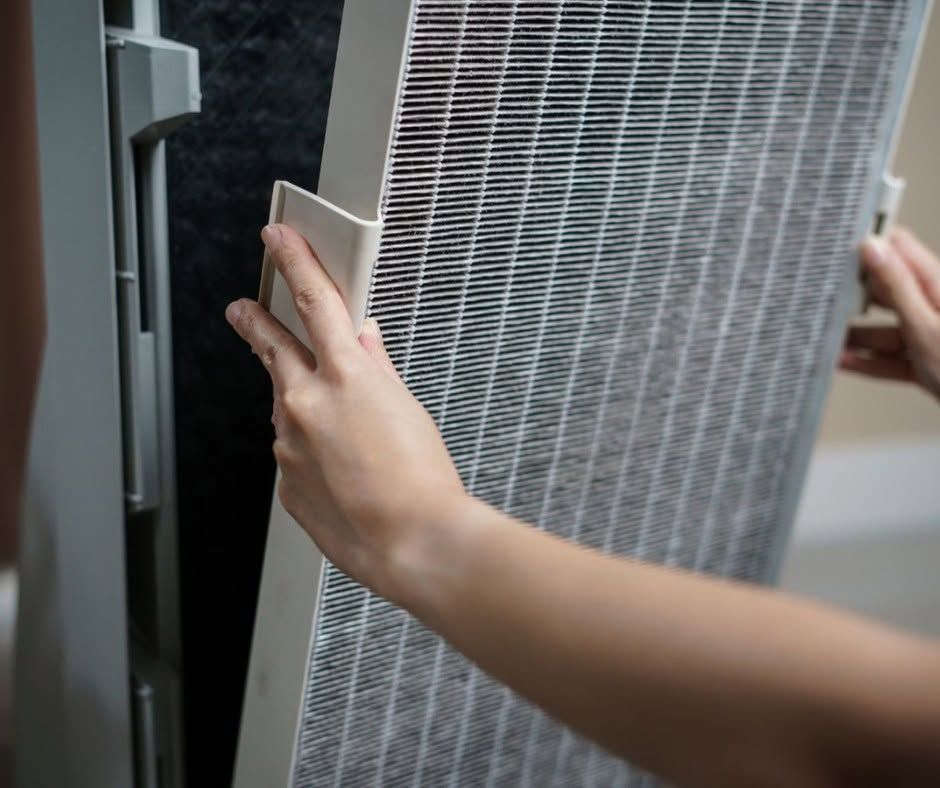 Person crouching in a narrow utility space, inspecting HVAC ducting and equipment.