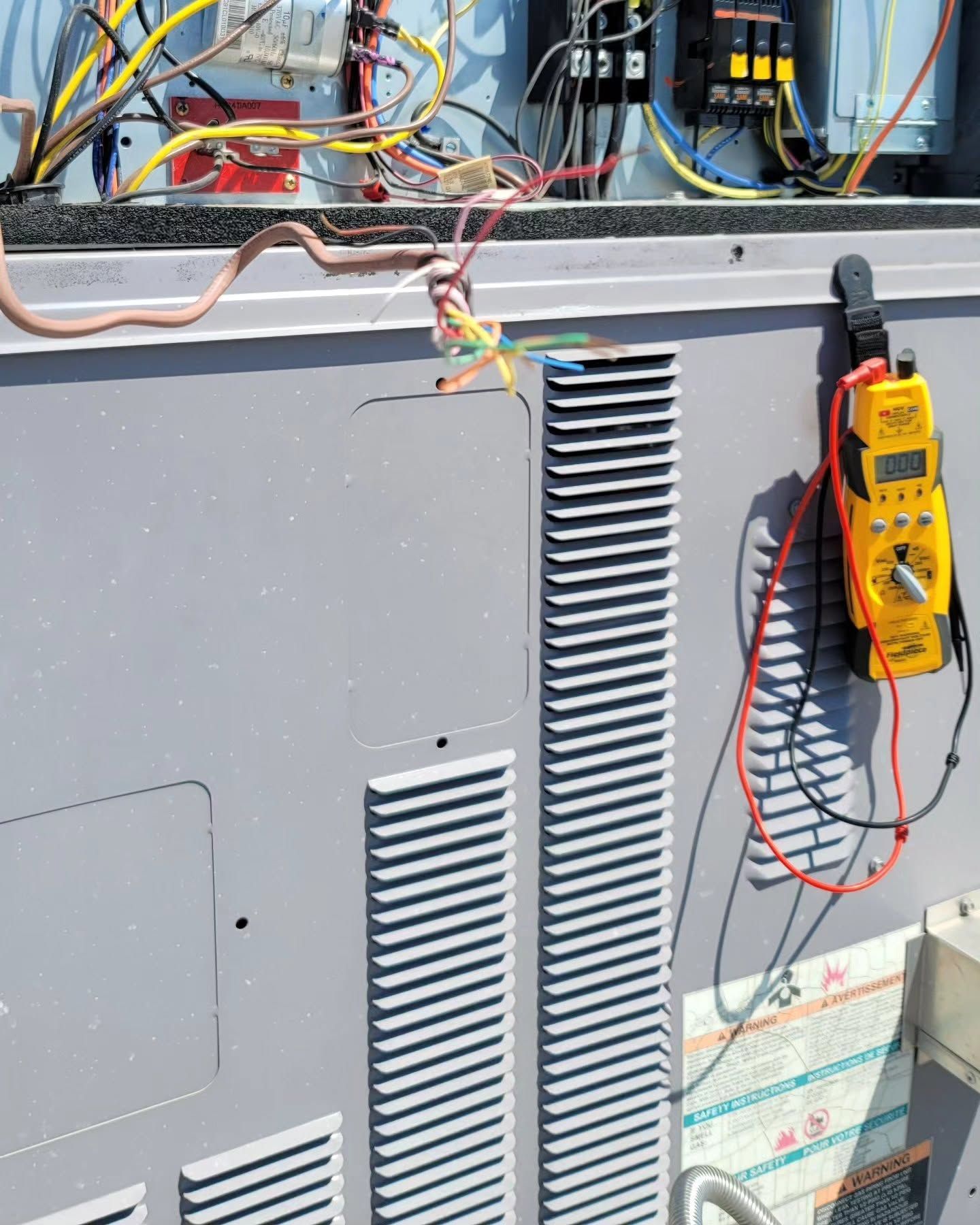 Person crouching in a narrow utility space, inspecting HVAC ducting and equipment.