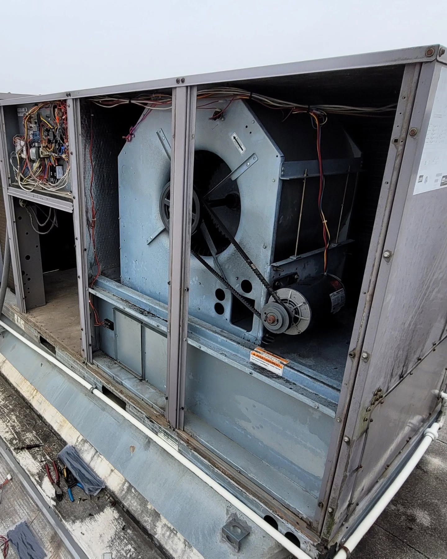 Person crouching in a narrow utility space, inspecting HVAC ducting and equipment.