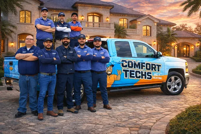 Nine uniformed technicians posing beside a blue Comfort Tech service van in a driveway at dusk