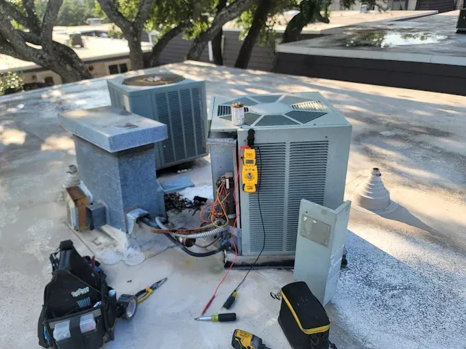 Outdoor HVAC units and tools scattered on a rooftop during maintenance.