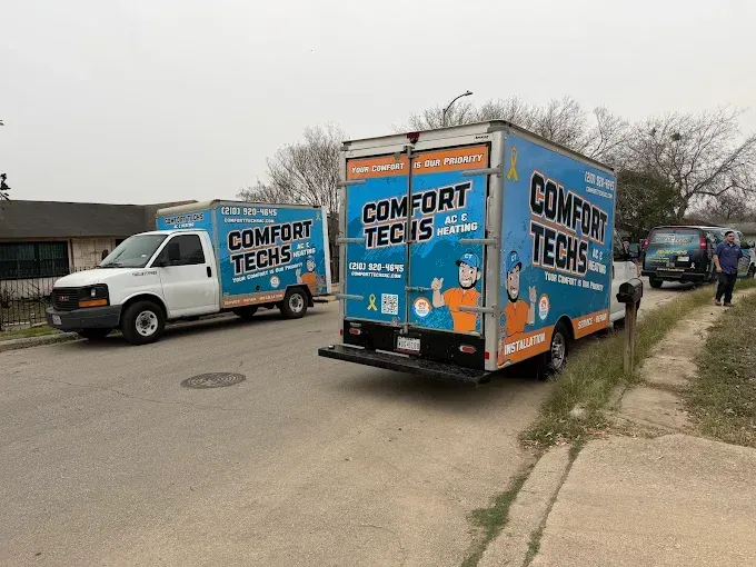 Two Comfort Techs vans parked on a street near a grassy sidewalk