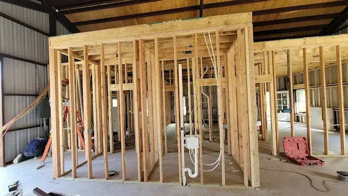 Interior framing of a building under construction with exposed wooden studs and roofing.