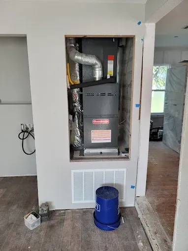 Open HVAC closet with furnace and ductwork in a hallway, blue bucket on the floor