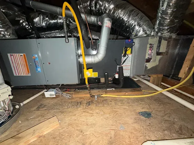 Utility room with HVAC unit, insulated ducts, and exposed floor joists in a crawlspace-like attic area