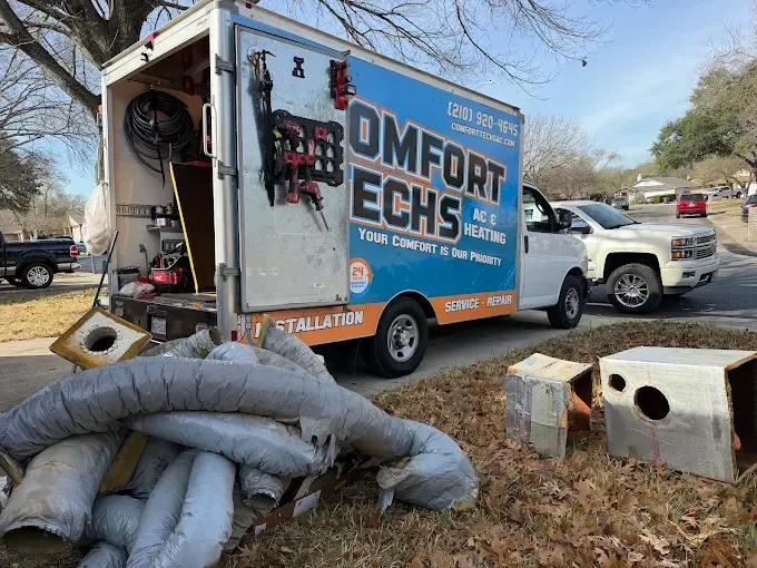 Dumpster with OMFORT Techs service truck, sandbags, and outdoor AC units at a roadside worksite