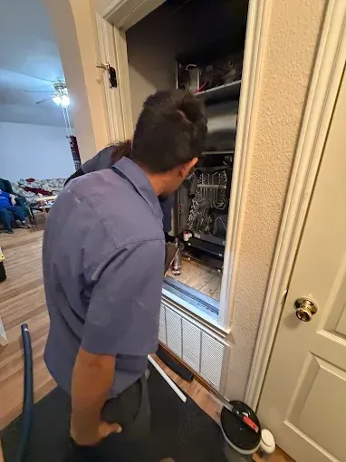 Person in a blue shirt inspecting an open closet with hanging clothes and shelves.