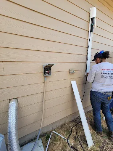 Person crouching in a narrow utility space, inspecting HVAC ducting and equipment.