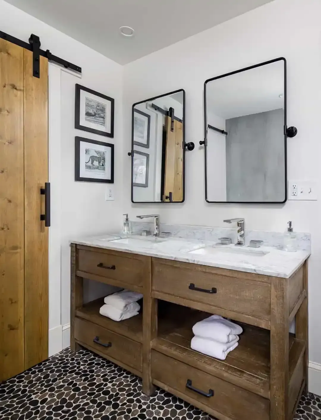 Modern bathroom with wooden vanity, double sinks, black-framed mirrors, and patterned tile floor.