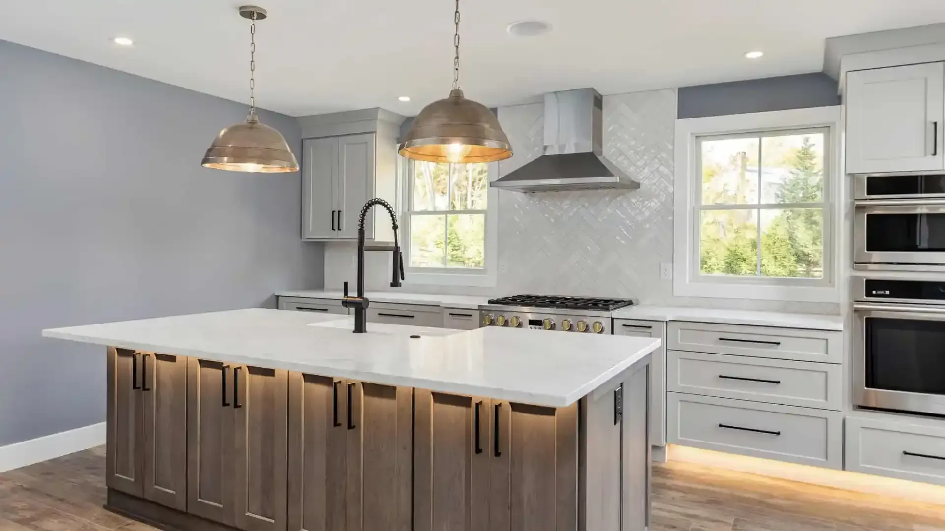 Modern kitchen with large island, pendant lights, white cabinets, and stainless steel appliances