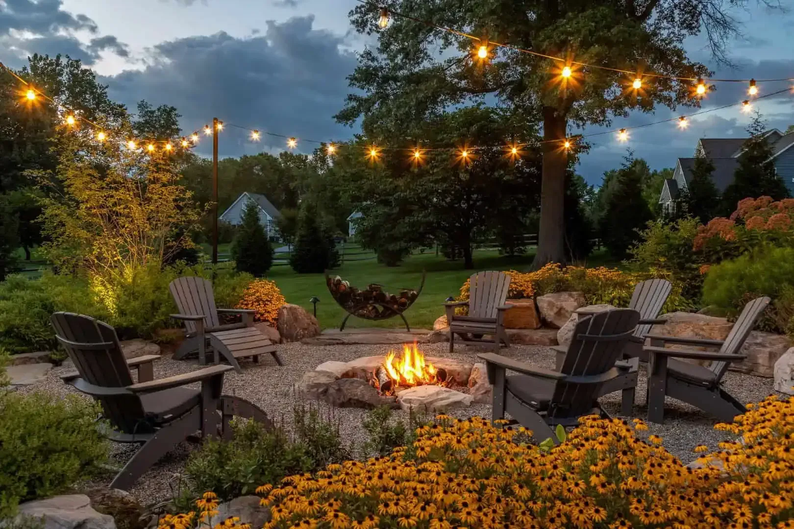 Cozy backyard fire pit surrounded by Adirondack chairs and string lights at dusk