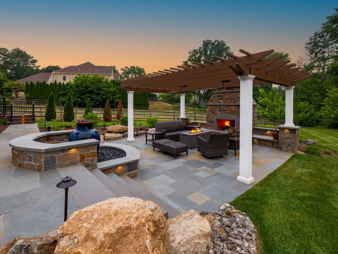 Backyard patio with pergola, fire pit, hot tub, and outdoor seating at sunset