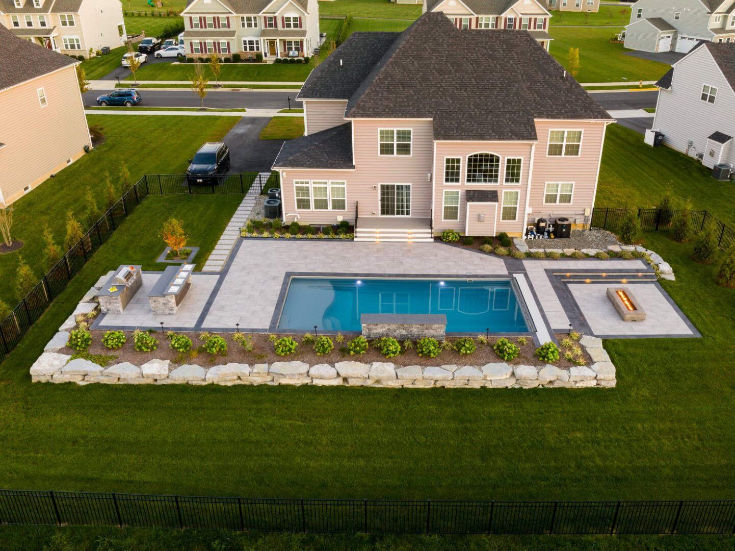Aerial view of a suburban house with a backyard pool, patio, and landscaped lawn.