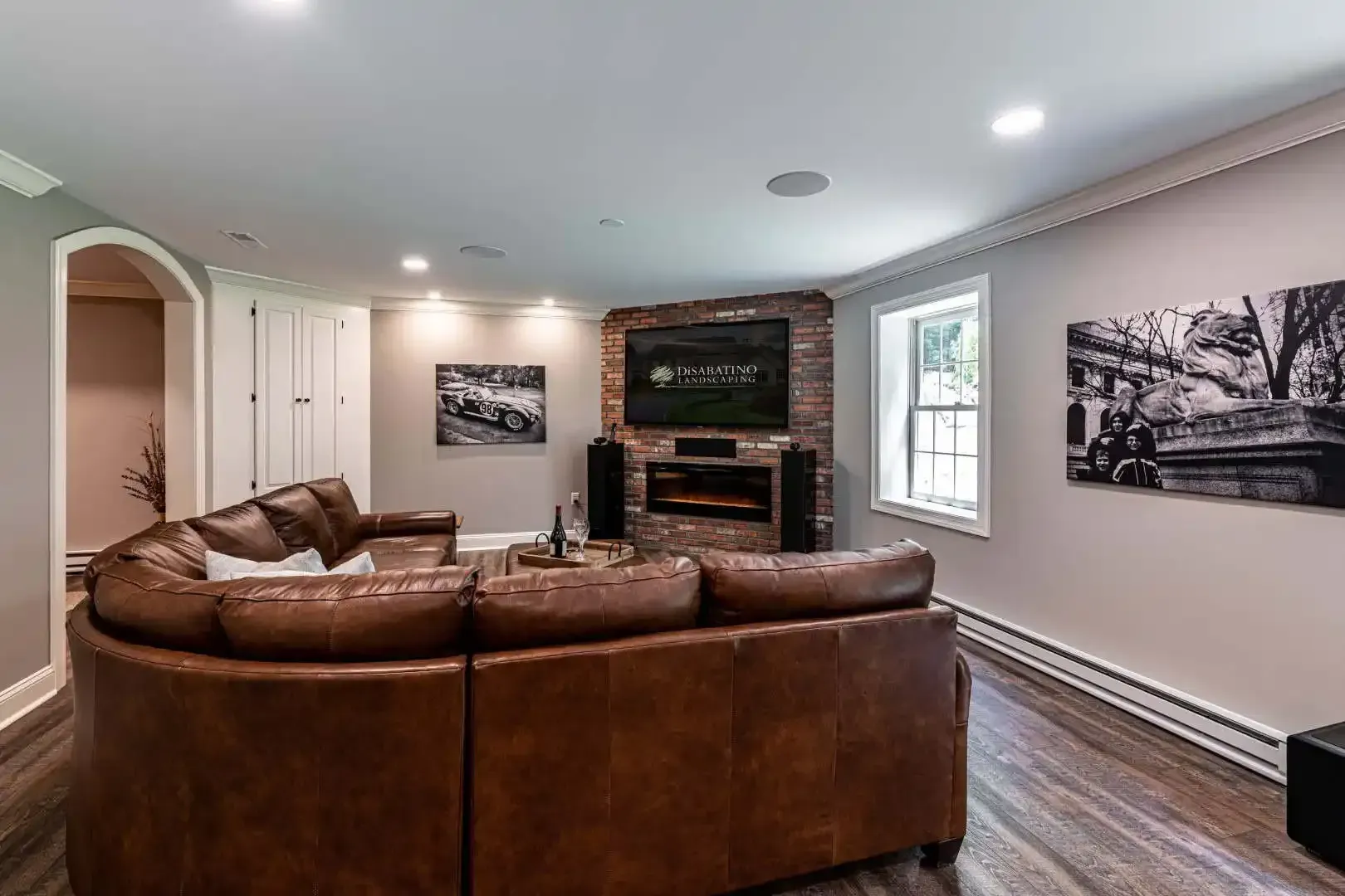 Living room with brown sectional sofa, fireplace, wall art, and hardwood floors