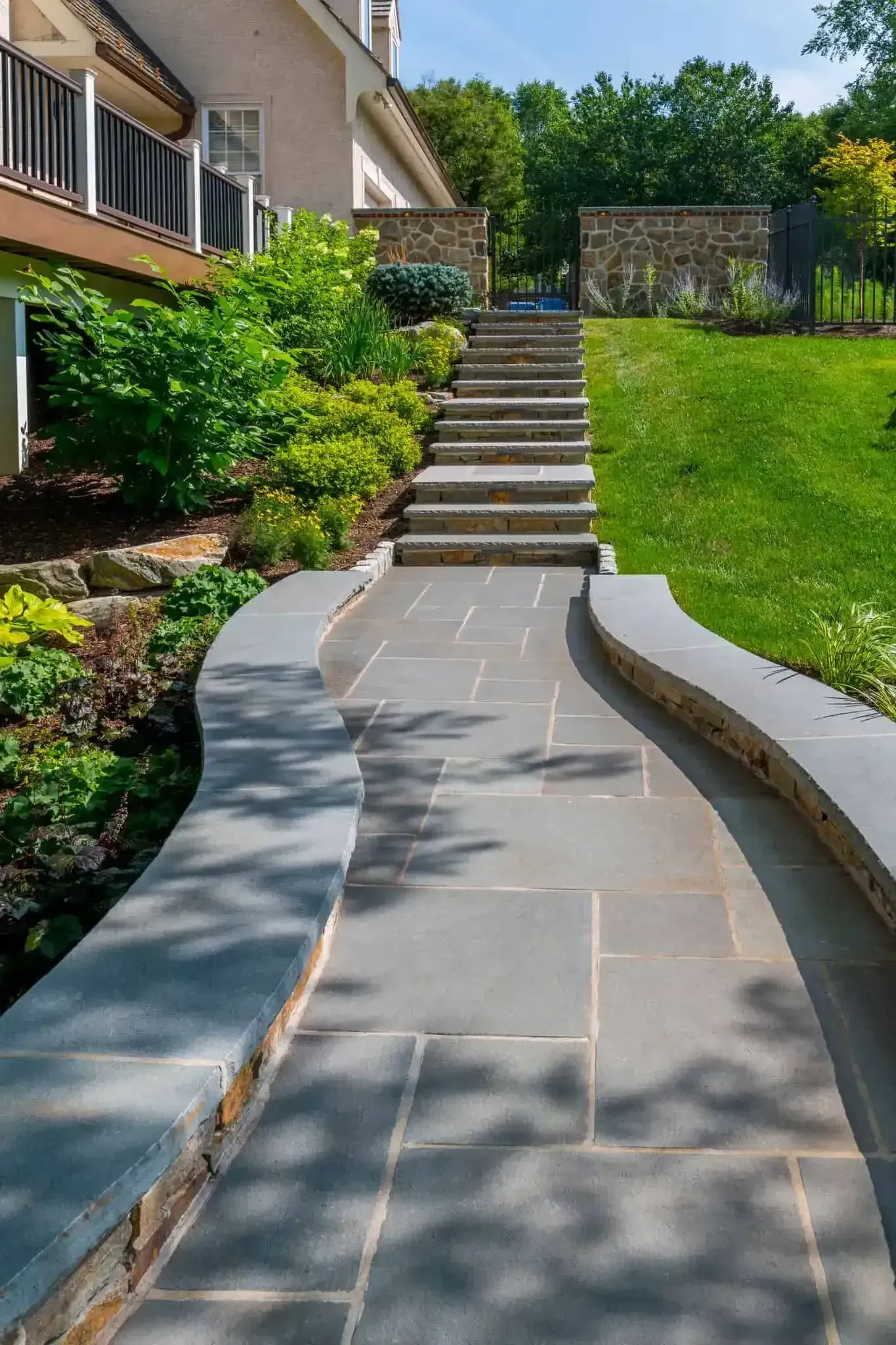 Curved stone walkway leading up steps through a landscaped garden beside a house