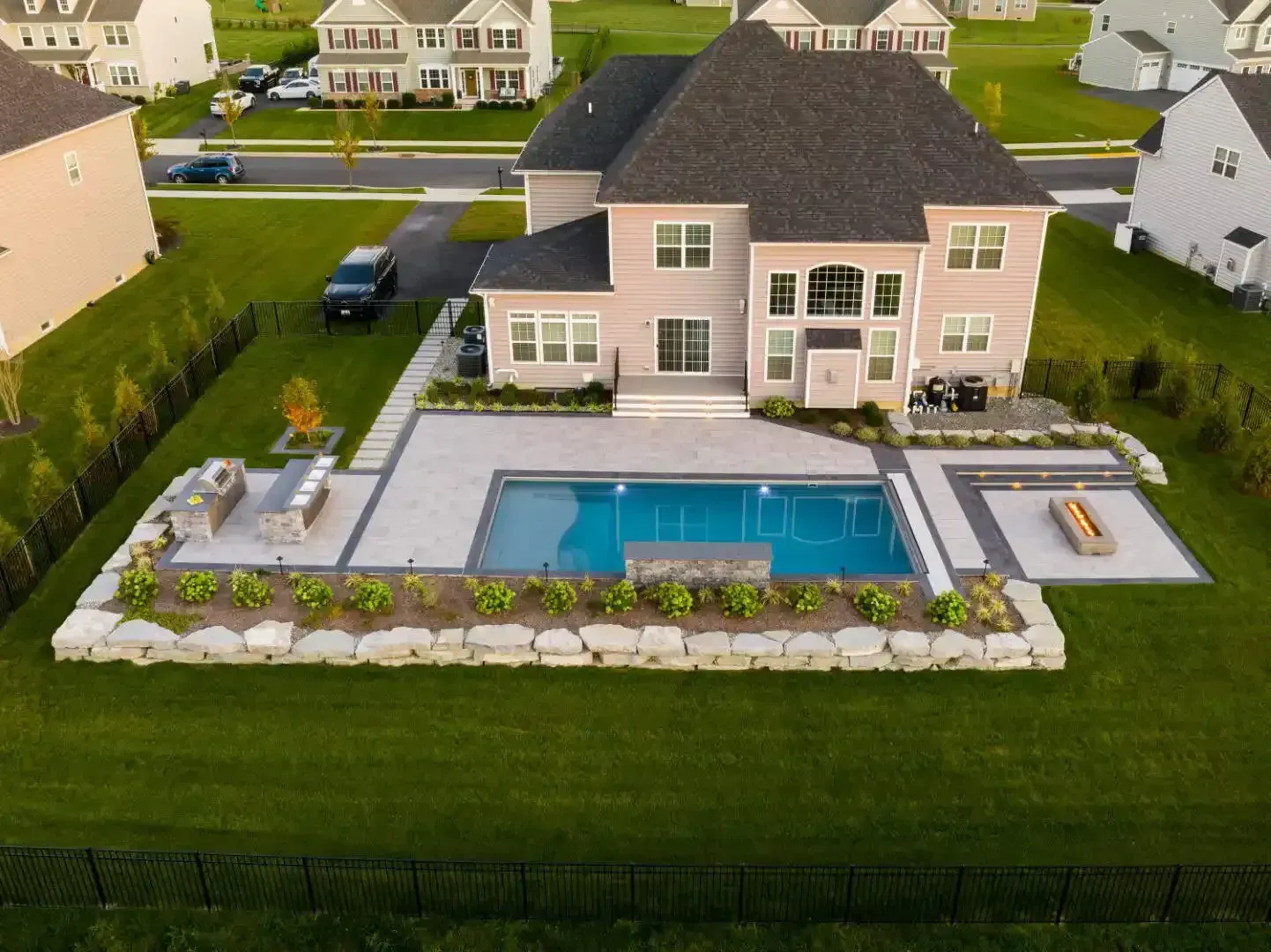 Aerial view of a suburban house with a large backyard pool, patio, and green lawn