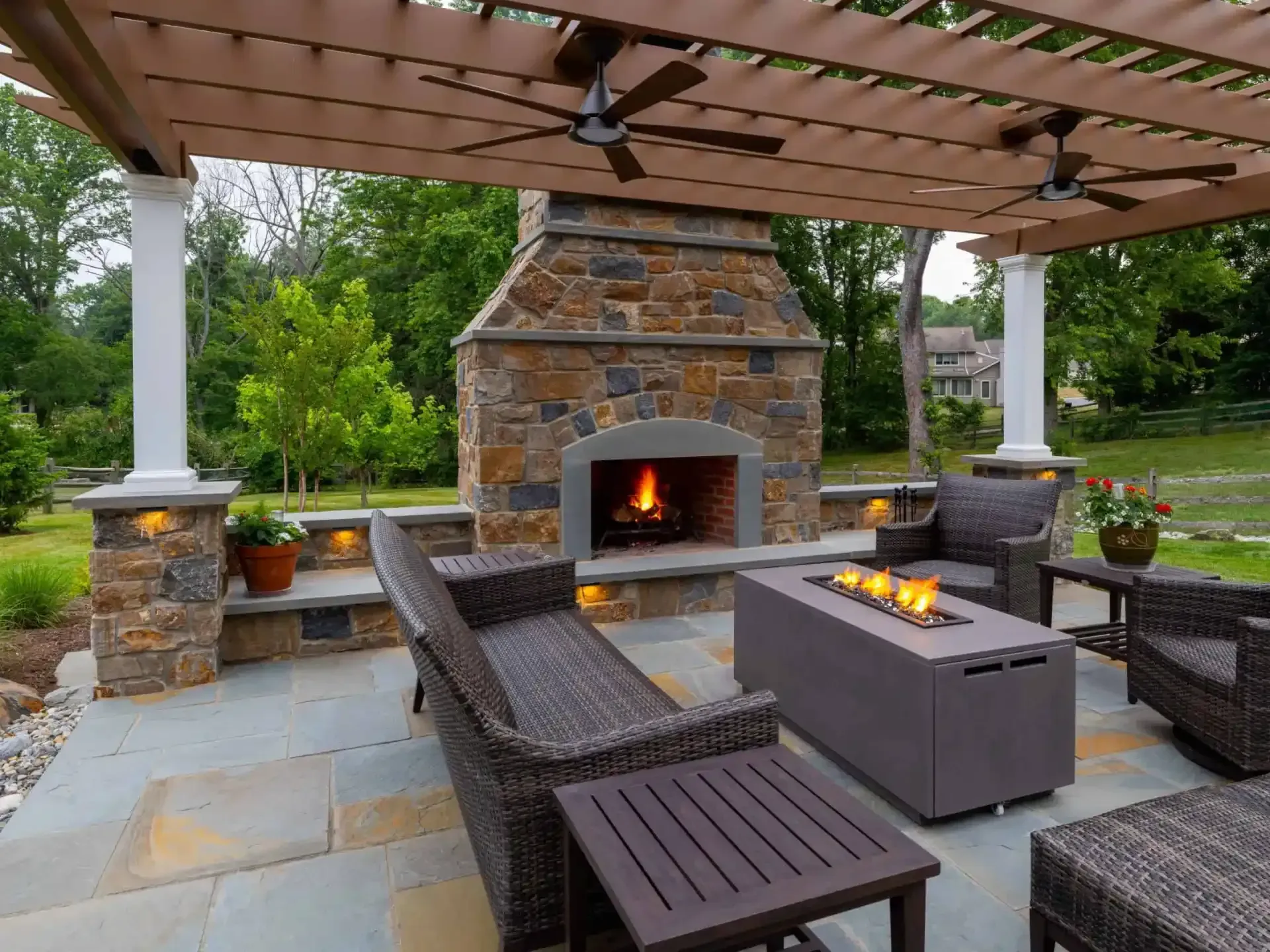 Covered patio with stone fireplace, outdoor seating, and a fire table under a pergola