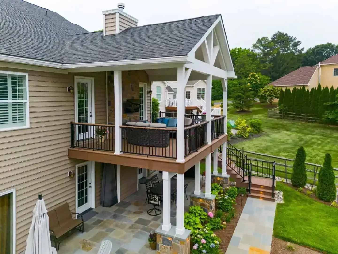 Two-story house with a covered deck and patio overlooking a landscaped backyard