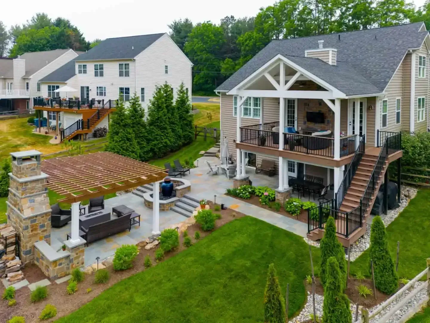 Suburban backyard with a covered patio, pergola, landscaped lawn, and two-story house