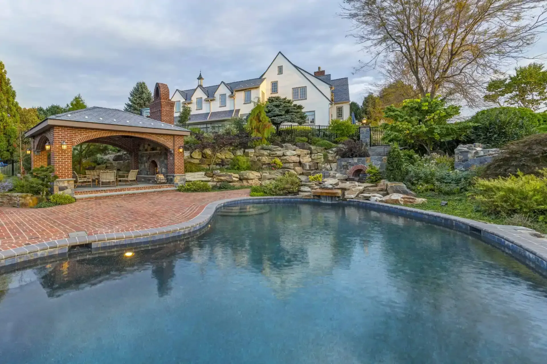 Luxury house with landscaped garden and curved pool beside a brick patio and gazebo
