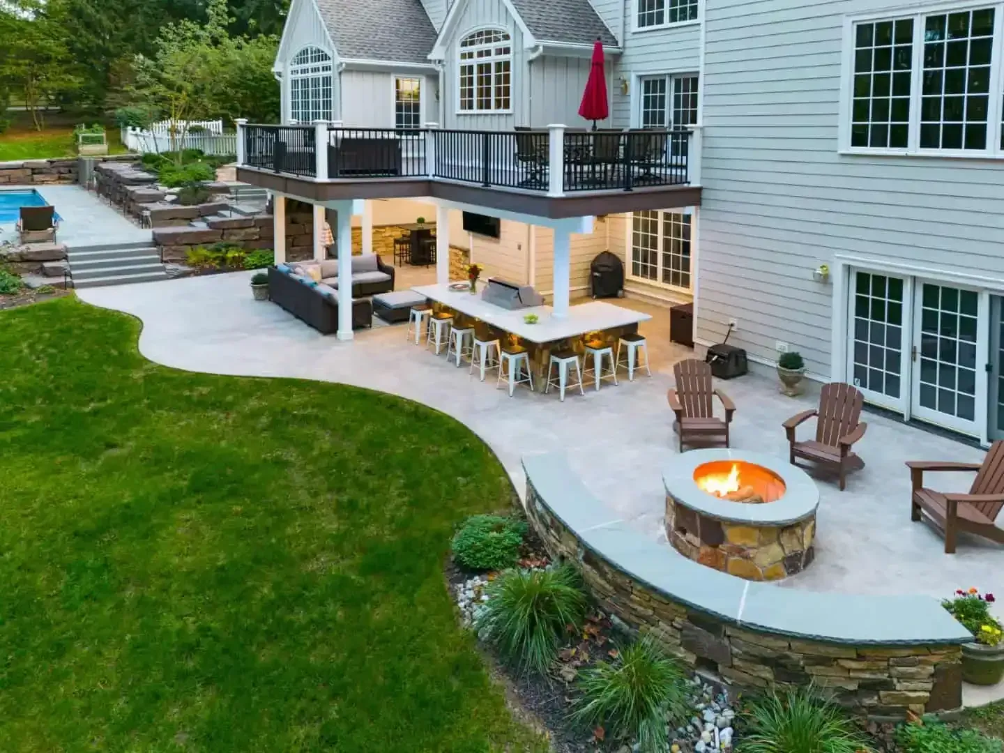 Backyard patio with outdoor seating, fire pit, and a covered deck beside a house