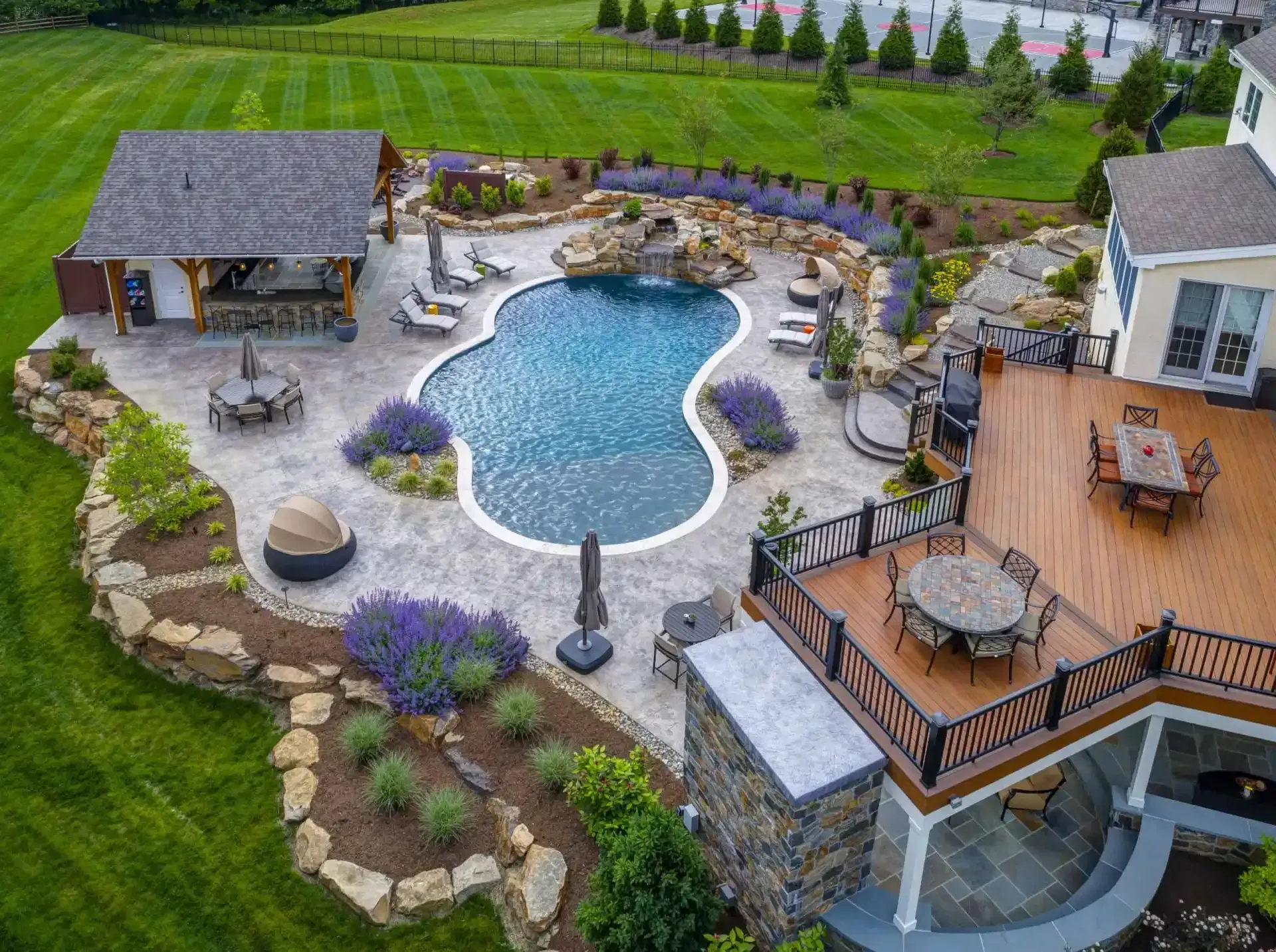 Backyard patio with a blue swimming pool, stone landscaping, and wooden decks