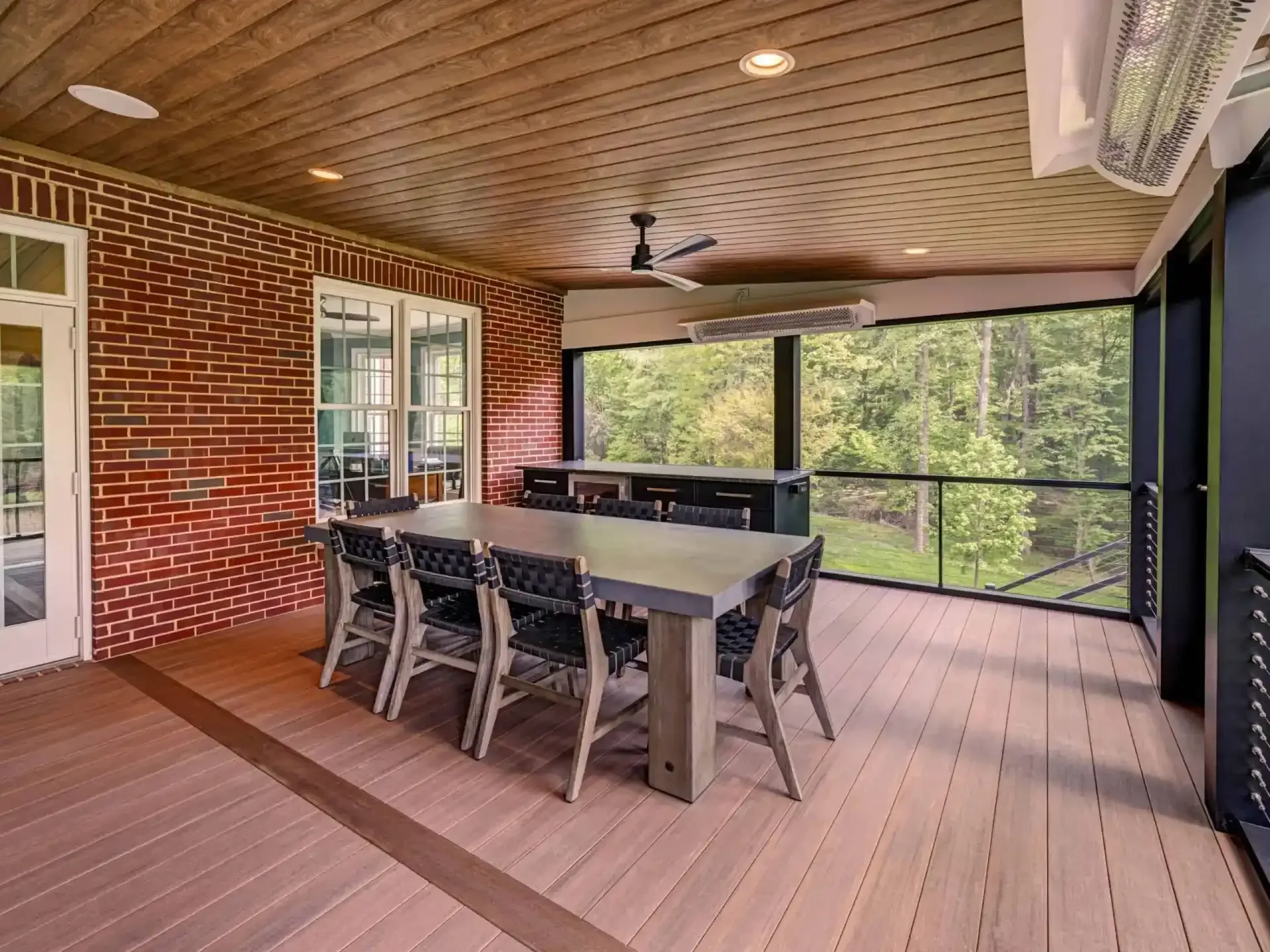 Covered screened porch with dining table, chairs, and outdoor view through large windows