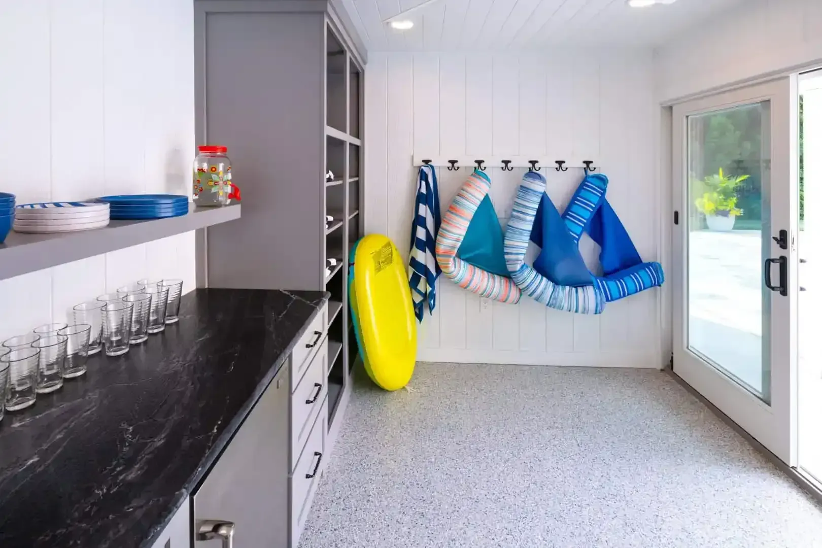 Bright laundry room with surfboards on wall, yellow board leaning by shelves, and a glass door to outside