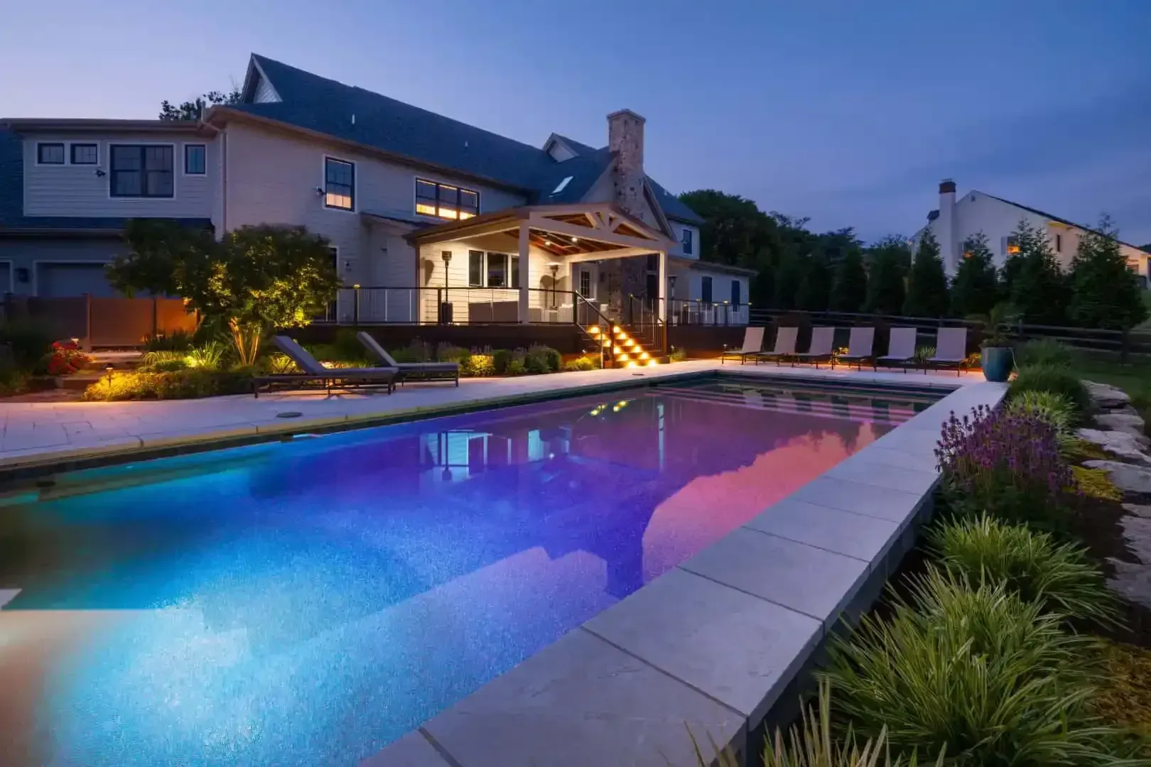 Modern house at dusk with a lit backyard pool and colorful reflections