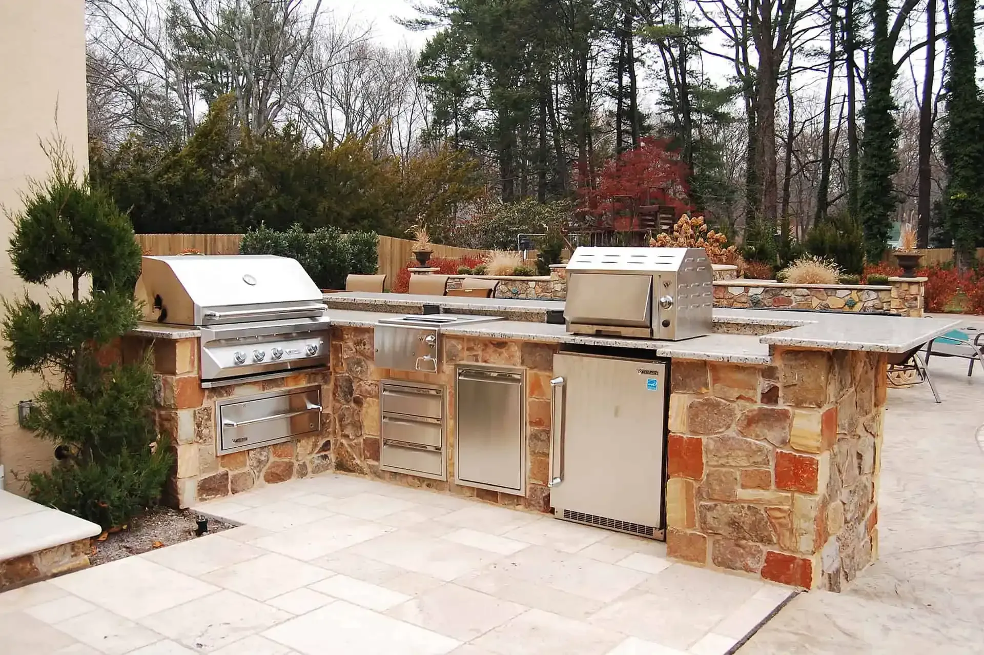 Outdoor stone patio with built-in stainless steel grill and cabinet kitchen setup