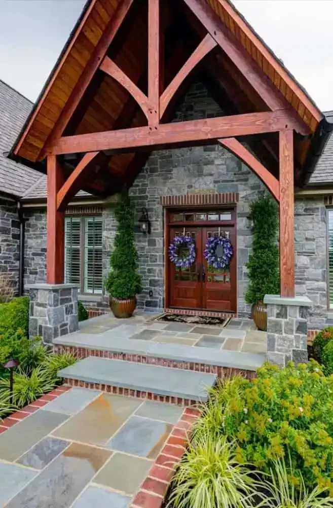 Stone house entrance with timber porch, double wooden doors, and colorful tiled walkway and steps