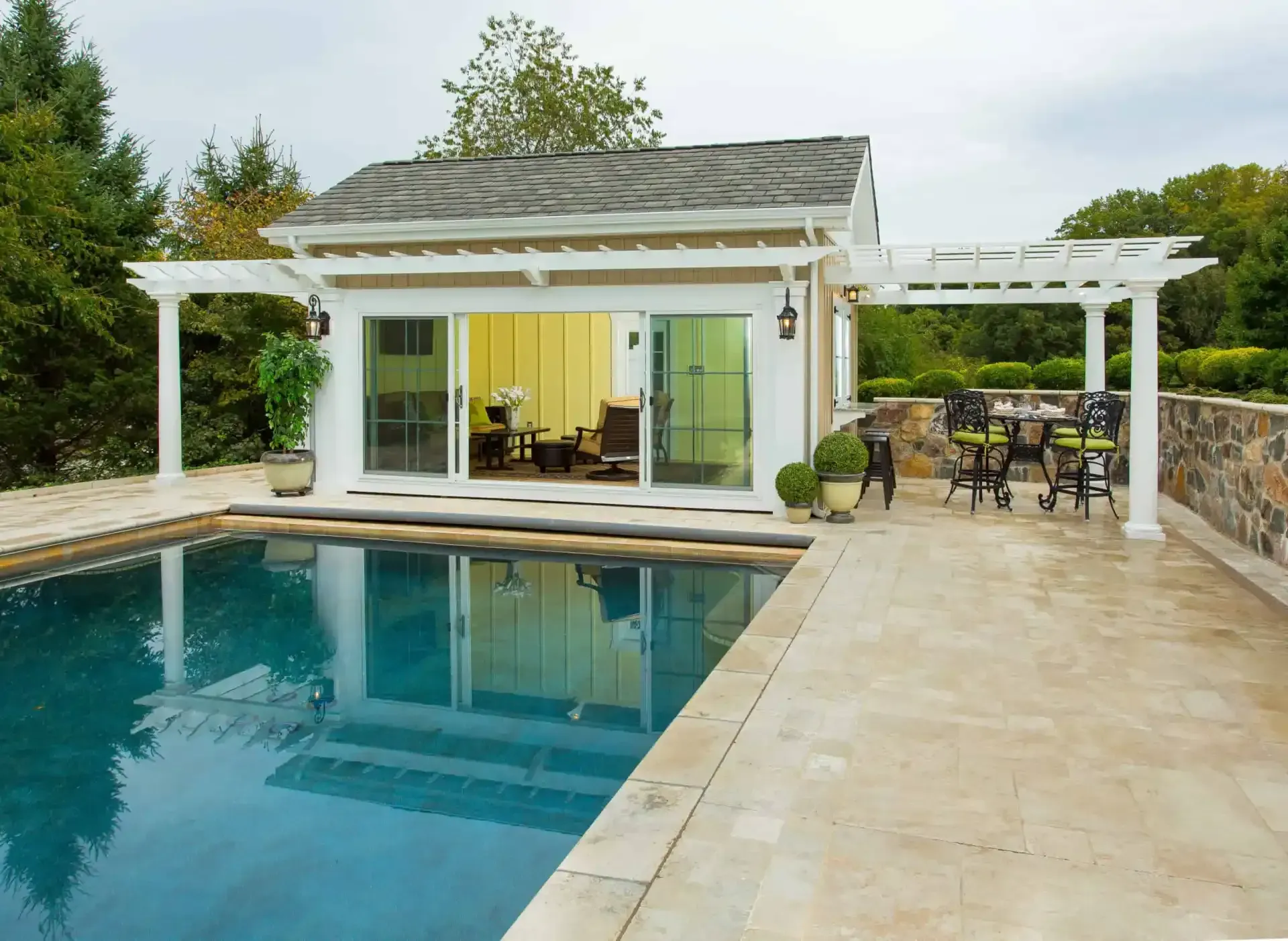 Modern backyard pool beside a small white patio house with lounge and dining area