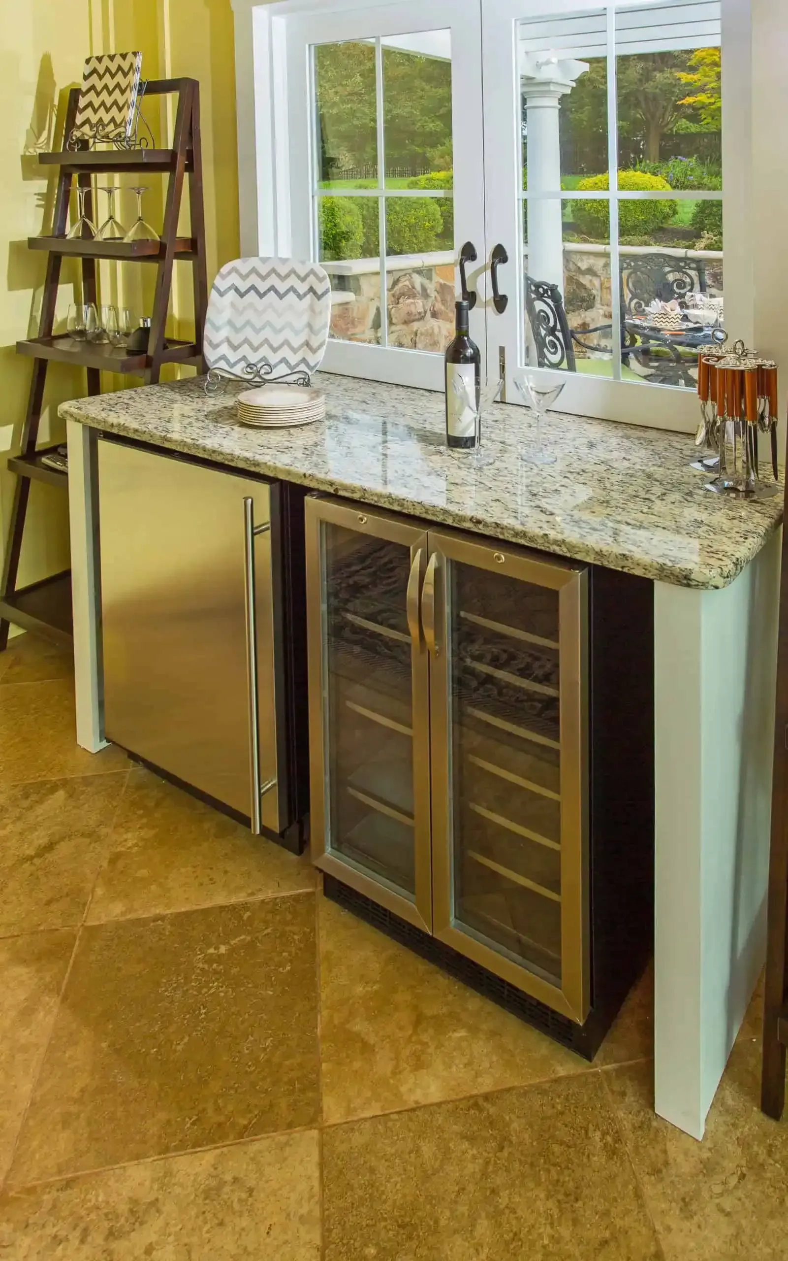 Modern kitchen island with granite countertop, built-in wine fridge, and large window overlooking greenery