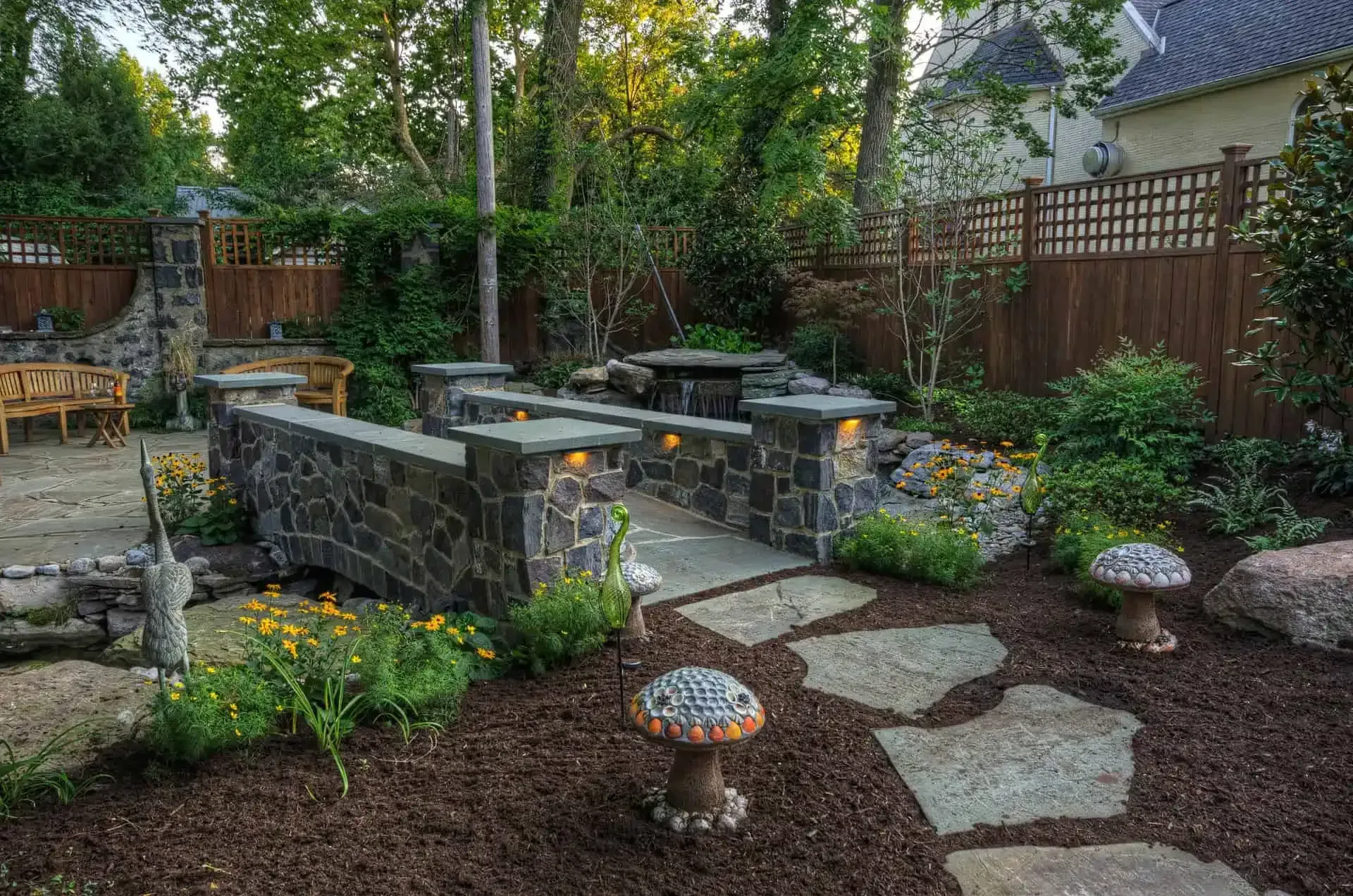 Stone patio with built-in benches and a stepping-stone path in a landscaped backyard garden