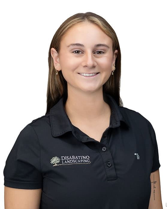 Smiling person in a black polo shirt with a logo, standing against a white background