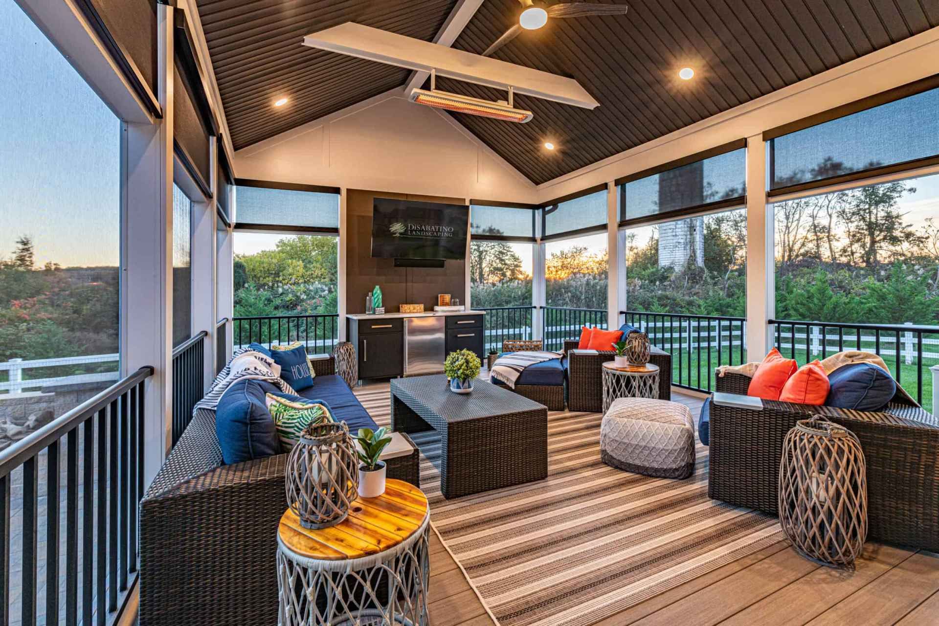 Covered patio with wicker seating, cushions, and string lights overlooking a sunset view.