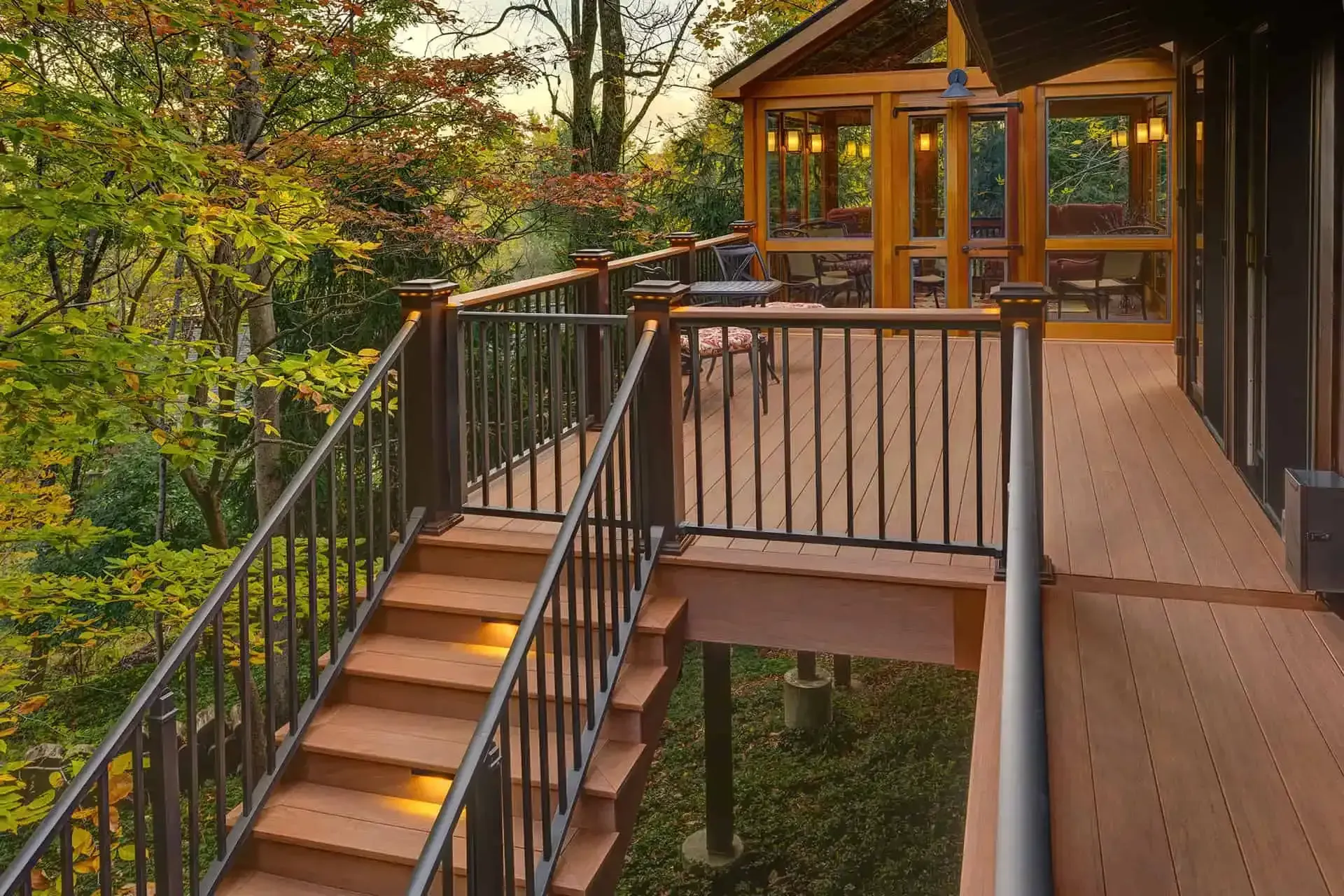 Wooden deck with stairs and railings leading to a gazebo in a wooded outdoor setting