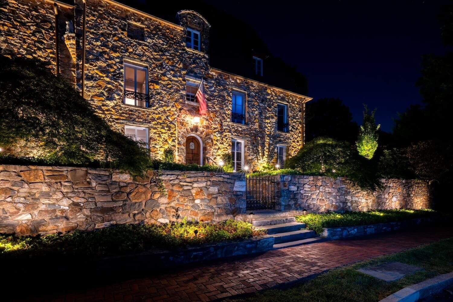 Illuminated stone building with arched doorway and lit landscape walls at night