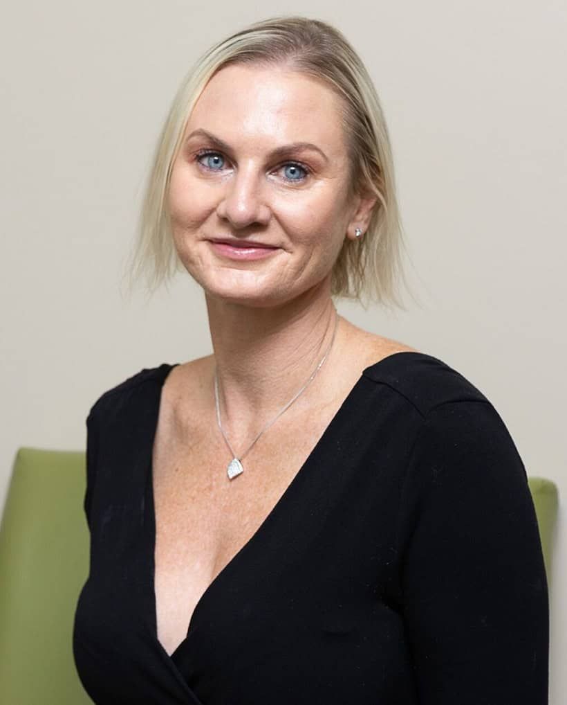 Portrait of a smiling blonde woman in a black top against a neutral background