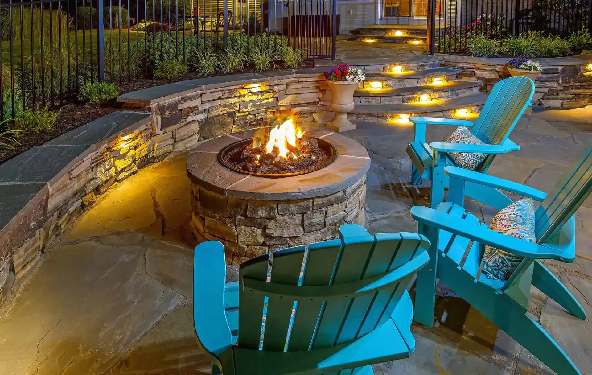 Backyard fire pit with turquoise Adirondack chairs at dusk