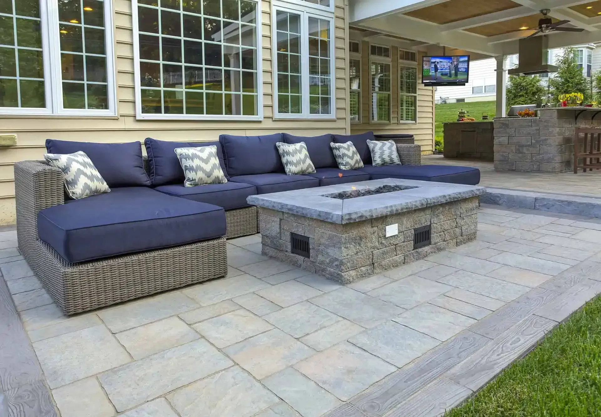 Outdoor patio with gray wicker sectional, navy cushions, and a stone coffee table under a covered porch