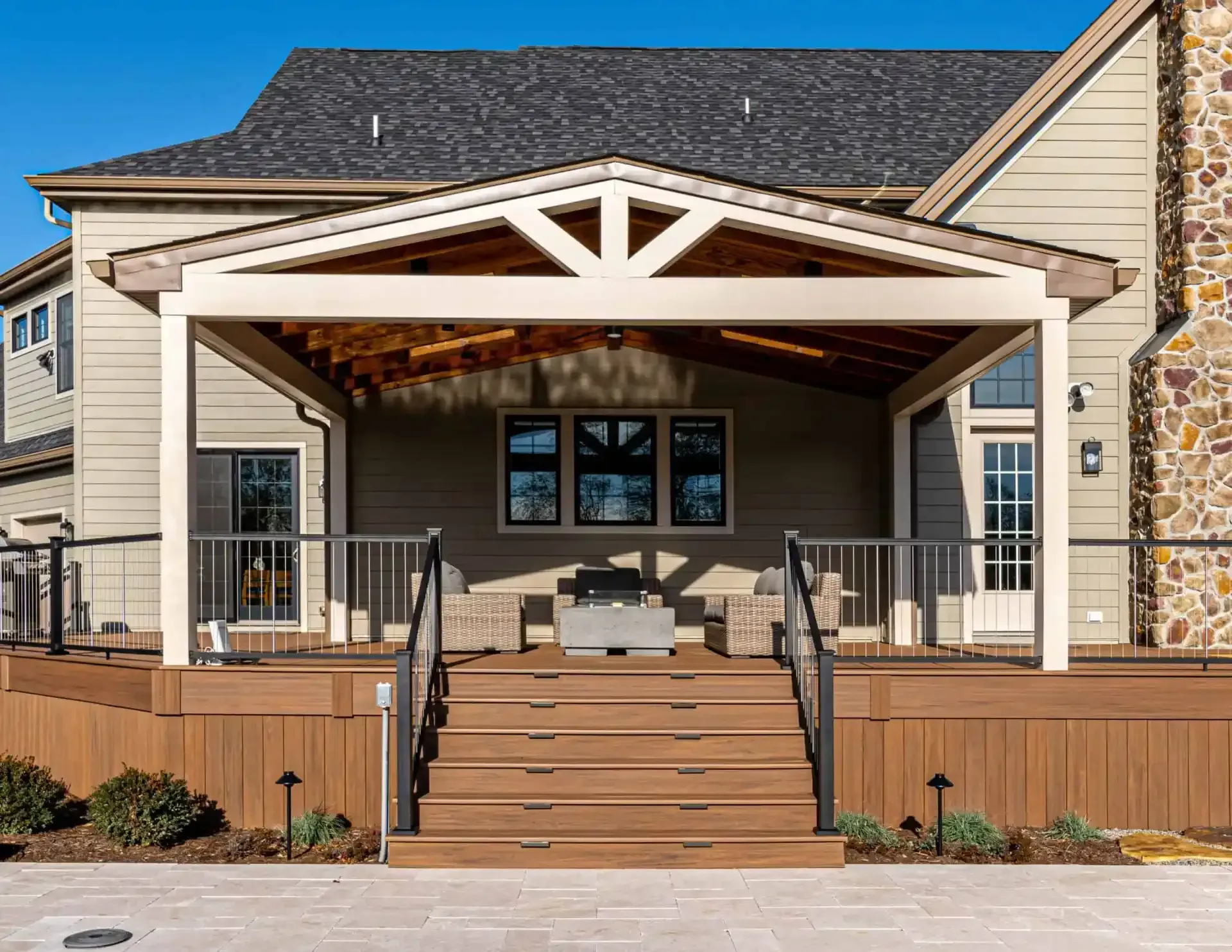 Covered front porch with wooden steps, white railings, and beige siding on a suburban home