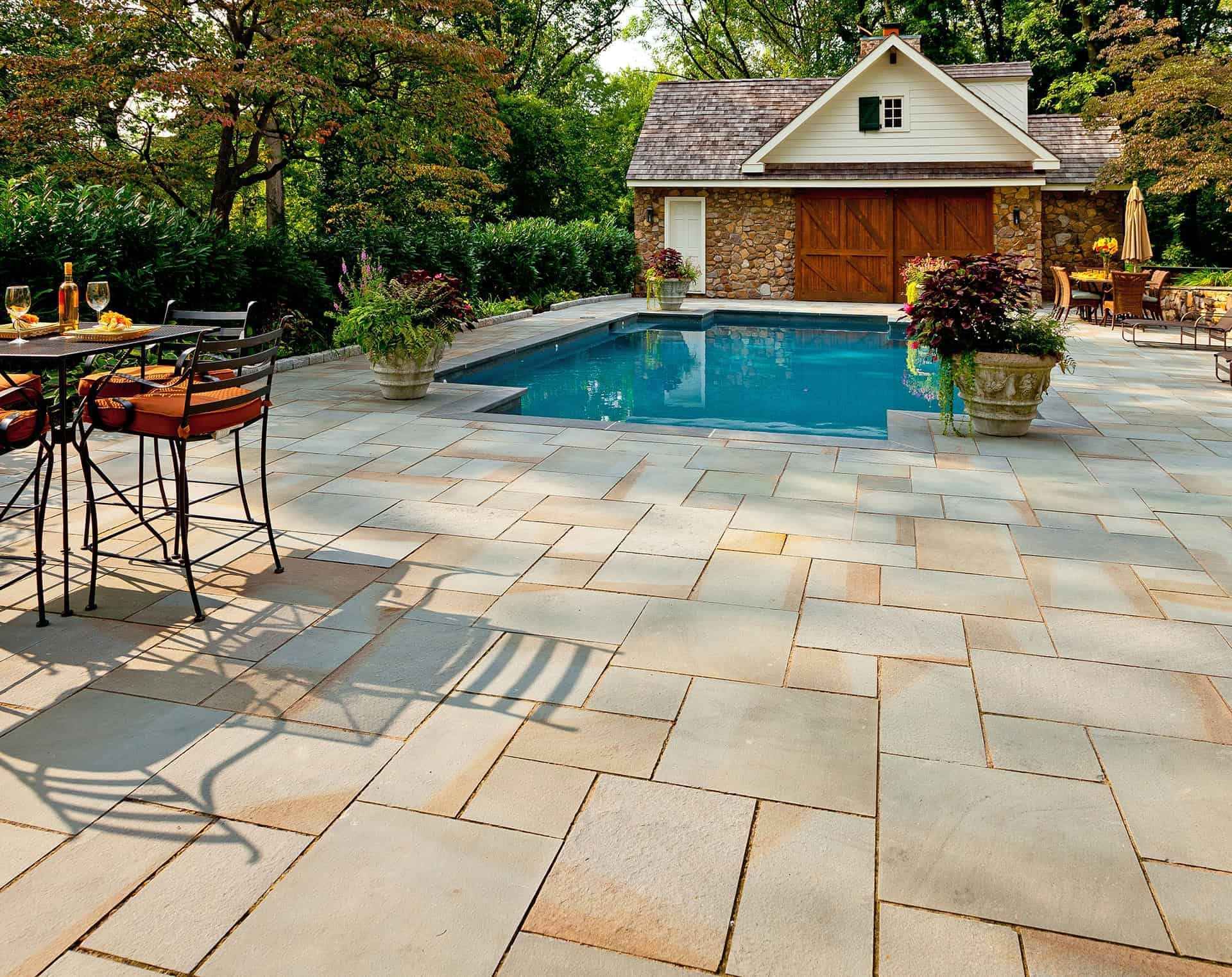 Backyard patio with a small blue pool, stone pavers, and a garden shed surrounded by trees.