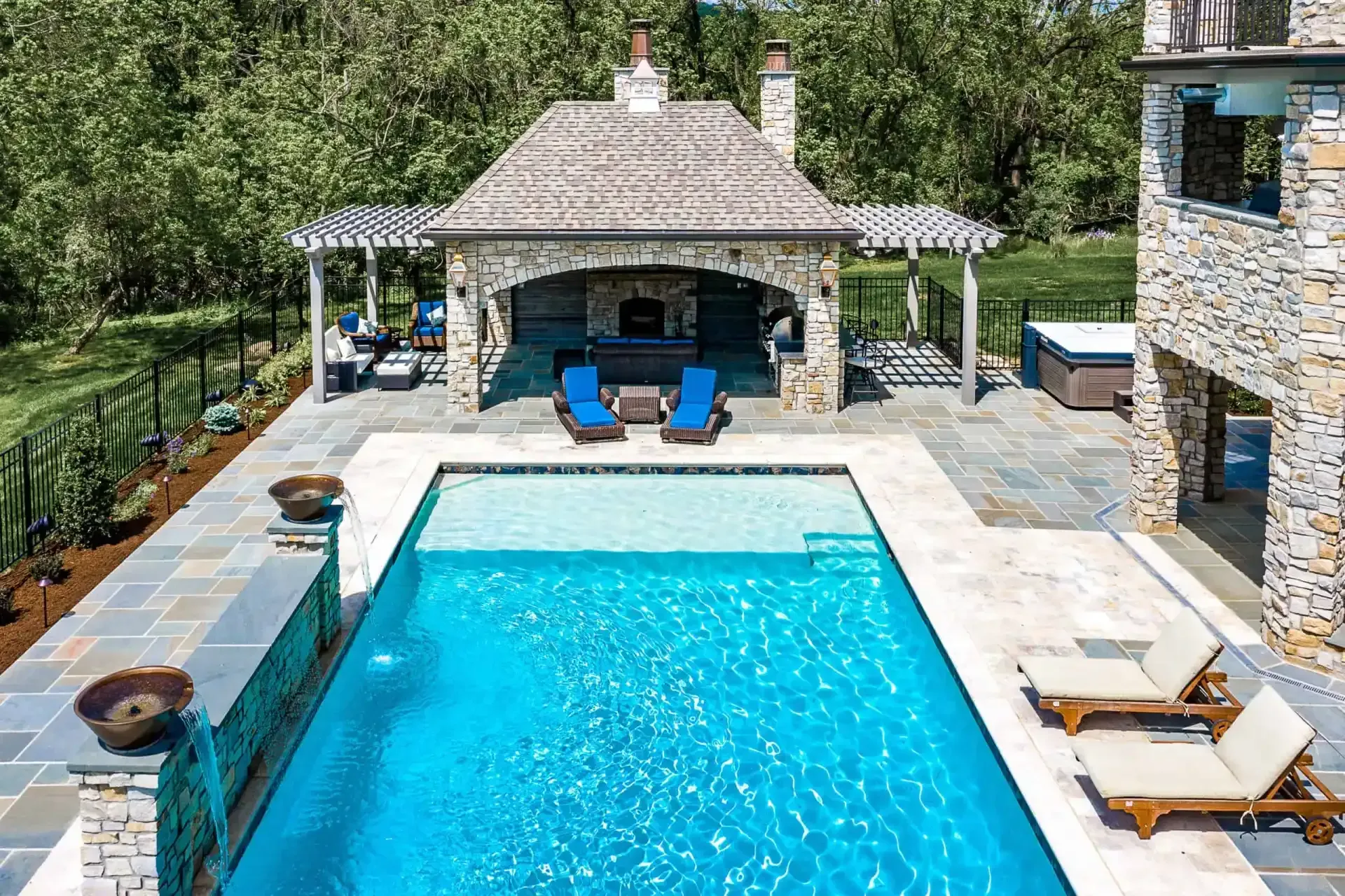 Backyard pool with stone patio, lounge chairs, and a cabana with blue seating